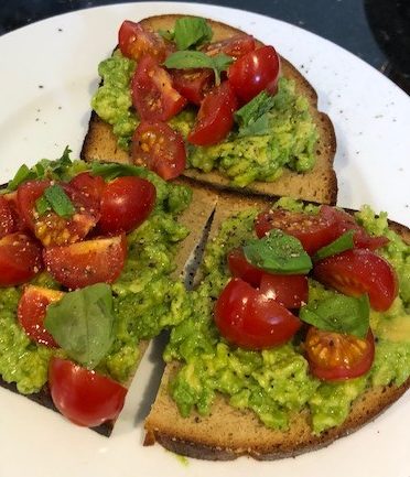 Smashed avocado and cherry tomatoes on toasted dutch rye bread, with fresh basil leaves